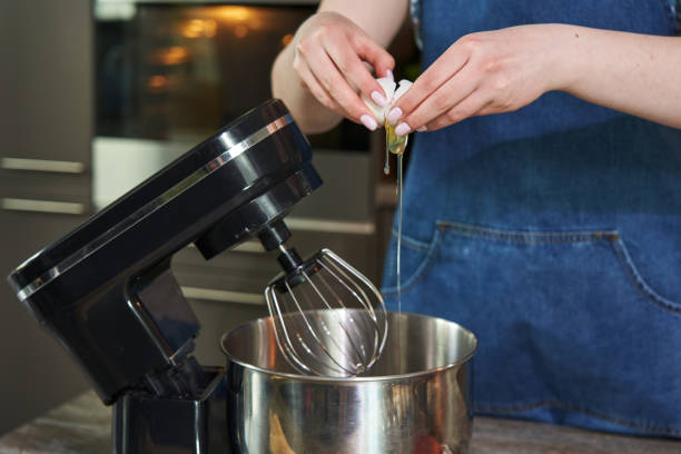 istock a woman's hand breaks a chicken egg into a large culinary mixer 1413977082