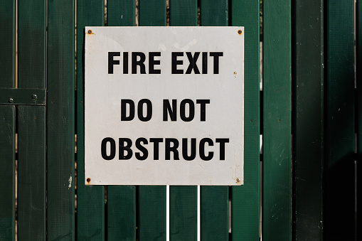 Old Silver fire door and sprinkler valve sign on a green wooden gate.