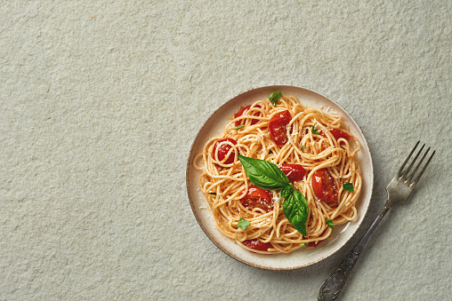 Spaghetti with cherry tomatoes top view with copy space on marble background studio shot