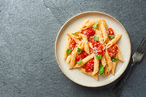 Penne pasta with cherry tomatoes on grey background top view with copy space studio shot horizontal