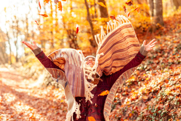 istock Woman throwing colorful fallen autumn leaves 1413990582