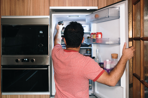 A man picking something from inside a refrigerator