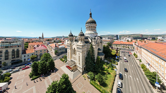 Aerial drone wide view of The Orthodox Cathedral located on the Avram Iancu Square in the centre of Cluj, Romania. Cityscape, central square, old buildings, cars