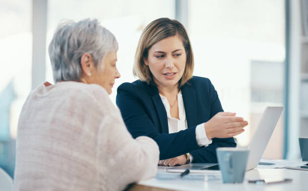 Elderly woman talking with legal agent and consultant about estate document on laptop. Senior, mature and aged pensioner gets money for retirement. Discussing contract for investment or settlement. stock photo