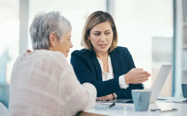 Photo of Elderly woman talking with legal agent and consultant about estate document on laptop. Senior, mature and aged pensioner gets money for retirement. Discussing contract for investment or settlement.