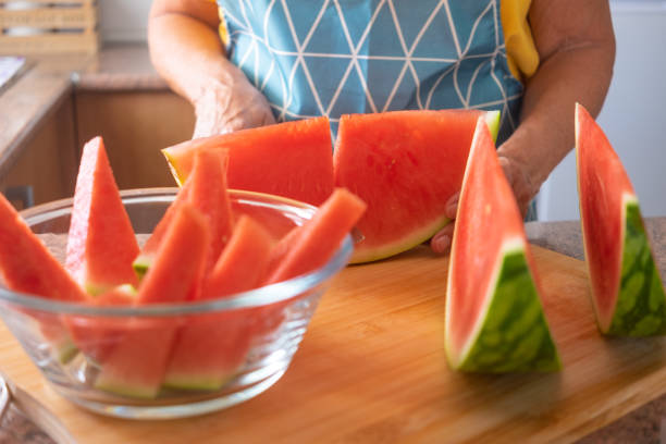 mani femminili che tagliano un cocomero fresco a fette e poi a triangoli - concetto di alimentazione sana - triangle human hand house home interior foto e immagini stock