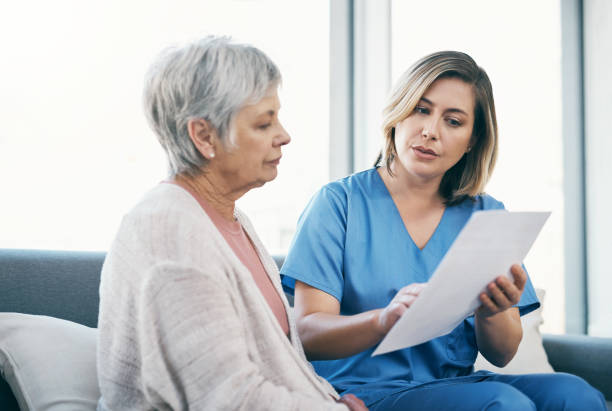 infermiera che mostra i risultati dei test alla donna anziana su carta e parla, discute e condivide le opzioni di trattamento nella casa di riposo. caregiver, custode o operatore sanitario medico che aiuta la signora anziana - serious nurse doctor ethnic foto e immagini stock