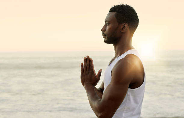 istock Calm man with prayer hands practicing yoga Anjali mudra, namaste pose with palms together for healthy lifestyle. One spiritual man praying or meditating on beach with sunset sky copy space background 1413996693