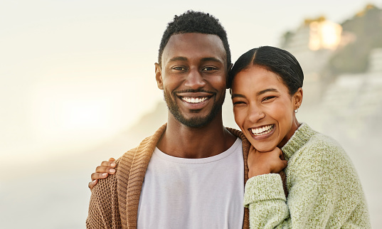 Loving and affectionate couple enjoying the weekend together outdoors at the beach and hugging. Portrait of a happy African American lovers spending time together on vacation or on holiday