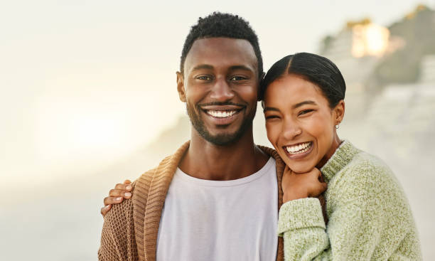 loving and affectionate couple enjoying the weekend together outdoors at the beach and hugging. portrait of a happy african american lovers spending time together on vacation or on holiday - couple black imagens e fotografias de stock