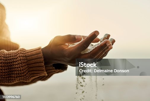 istock Closeup pouring sand through hands on the beach during sunset. Man holding or playing with soft soil grains while it runs through fingers outside in nature near the ocean in summer with copy space 1413996760
