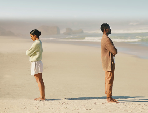 Sad, angry and stress, frustrated young couple standing apart after a bad argument at the beach. Woman and man with poor communication breaking up, ending relationship and ignoring a problem