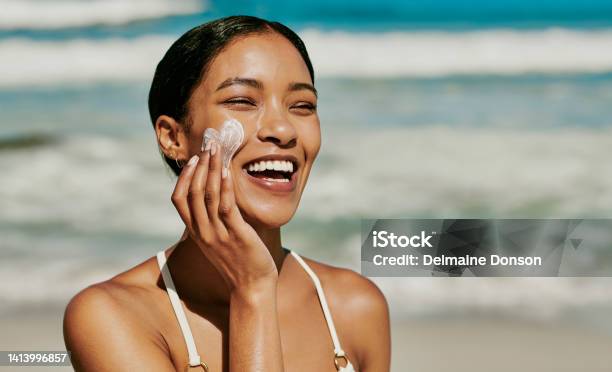 Young Woman Applying Sun Lotion To Her Face For Protection From Uv While Having Fun At The Beach Outside On Vacation Beautiful African Female With Natural And Perfect Skin Using Her Hands Spf Cream Stock Photo - Download Image Now