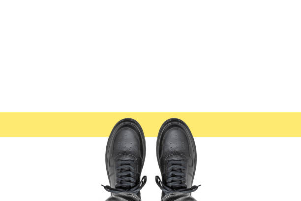 Black leather shoes on a white background. Top view of young male feet wearing sneakers.