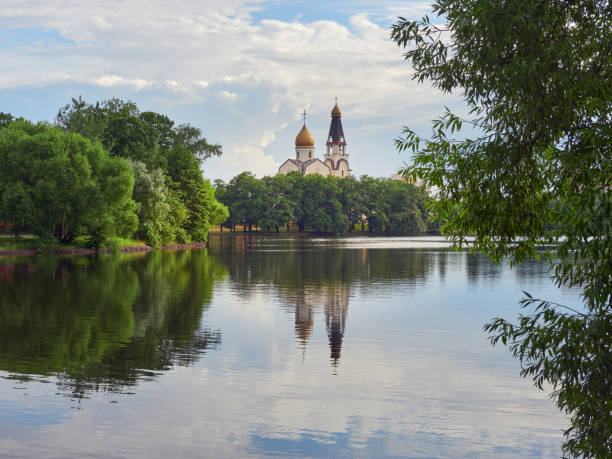 Orthodox church by lake on summer evening: clouds reflected in water.