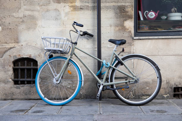 bicicletta incatenata a un palo sul marciapiede di una strada secondaria di parigi - wheel cycling nobody outdoors foto e immagini stock