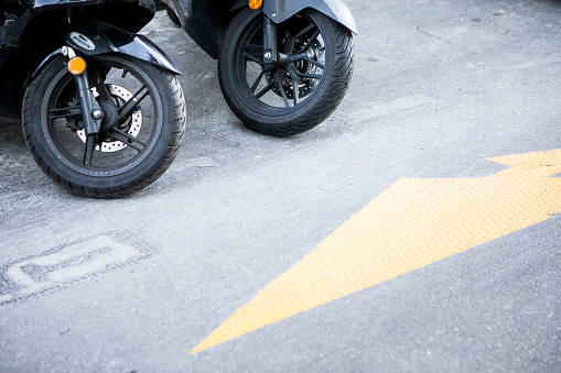 Two moped wheels and a yellow arrow symbol in a Paris street
