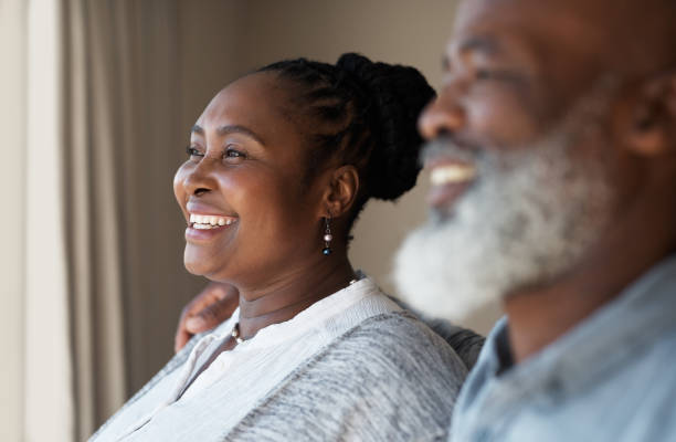 istock Happy, cheerful and retired couple smiling and feeling satisfied while thinking about retirement and insurance while standing together at home. African husband and wife looking pleased about future 1413999844