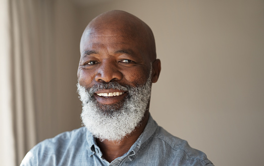 Face portrait of a happy black senior at home, relaxing and enjoying retirement. Closeup of a mature African American male laughing, looking satisfied, having relaxed day spending free time indoors