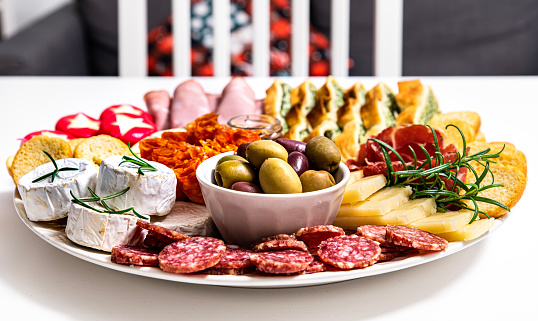 Italian cuisine shows inviting meal or appetiser composed of one tasty dish with pepperoni, crudo ham, brie cheese, salami and focaccia bread paired with salumi (cured meat), jam, rosemary and olives