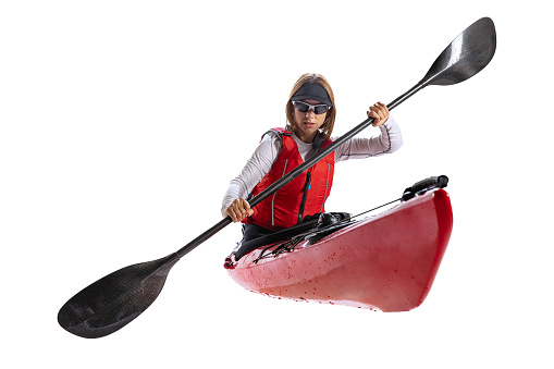 Rowing. Young woman, sportsman in red canoe, kayak with a life vest and a paddle isolated on white background. Concept of sport, nature, travel, active lifestyle