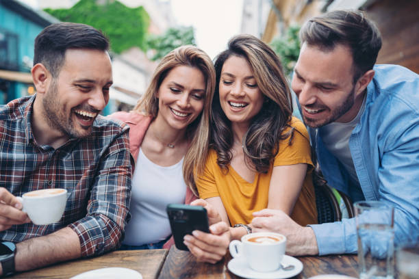 Group of friends sitting in cafe and looking at smart phone stock photo