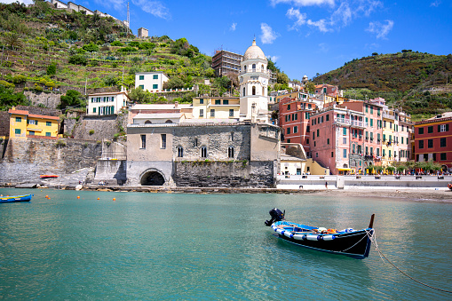 Vernazza, Cinque Terre - Italy, May 12, 2019: View on bay of water with moored boats and typical colorful houses in small village, Riviera di Levante
