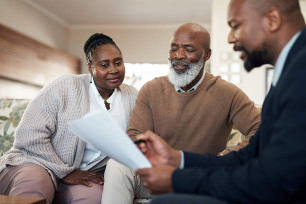 Mature, senior and married couple and a finance manager looking at retirement, savings and investment paper work. Man and woman planning a budget for their future with an accountant, banker or broker stock photo