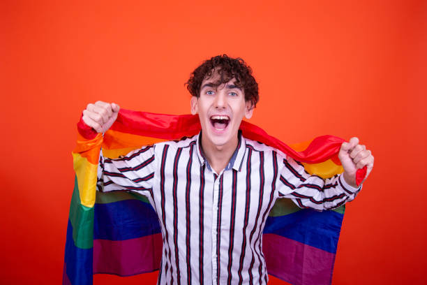 jovem atraente com uma bandeira de arco-íris. - flag gay man american culture rainbow - fotografias e filmes do acervo
