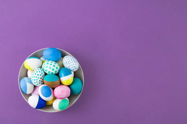 istock Colorful Easter Eggs in a Bowl on Purple Background 1414003877