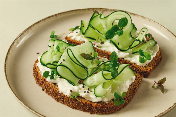 istock Breakfast, cereal bread sandwiches, cream cheese, sliced cucumber, with micro greenery on a light table, close-up, top view, selective focus, no people, 1414004170
