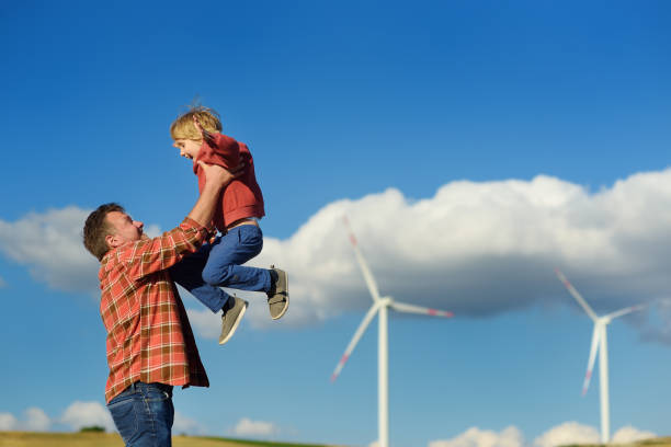 Eco activists man and child on background of power stations for renewable electric energy production. People and windmills. High wind turbines for generation electricity. Green energy stock photo