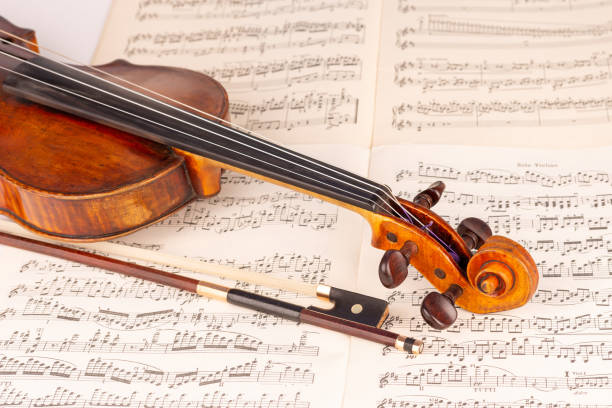 istock Old Classical Violin and bow with music sheets in the background 1414008213