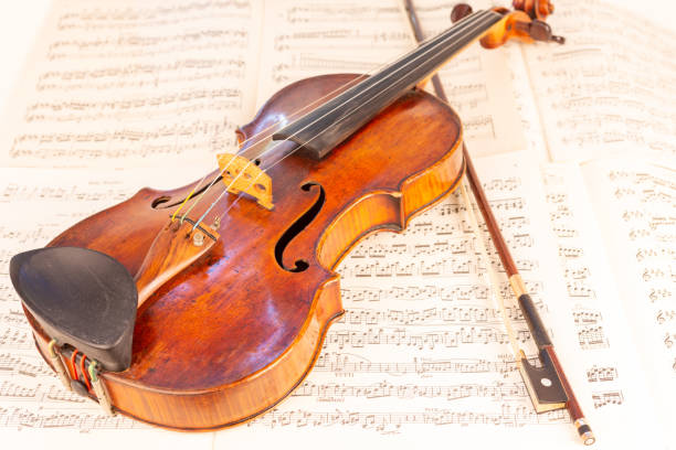 istock Old Classical Violin and bow with music sheets in the background 1414008382