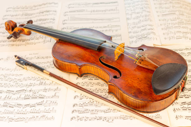istock Old Classical Violin and bow with music sheets in the background 1414008393