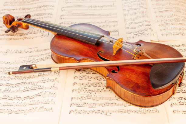 istock Old Classical Violin and bow with music sheets in the background 1414008487