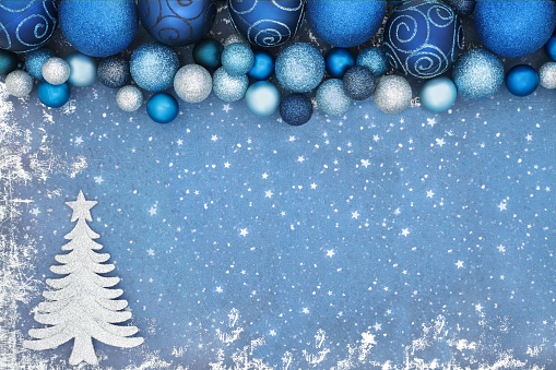 Christmas tree abstract background border on blue grunge with glitter bauble decorations. Xmas sparkling composition for the festive season.