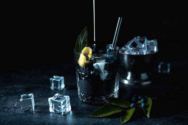 istock Black cocktail with lemon and ice on black background. 1414010228