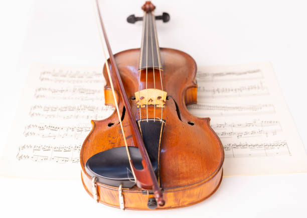 istock Baroque Violin and baroque bow with music sheets in the background 1414010378