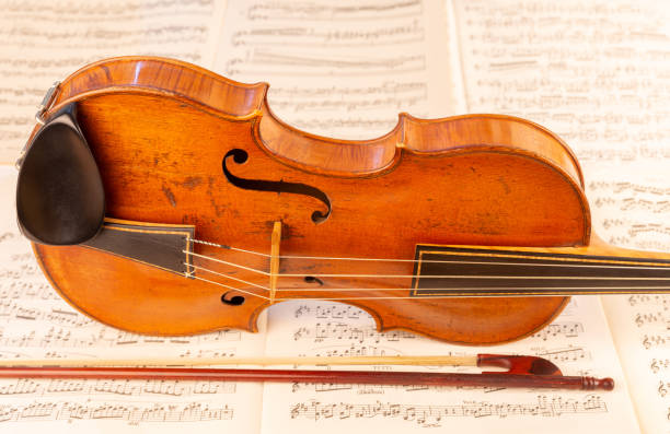 istock Baroque Violin and baroque bow with music sheets in the background 1414010381