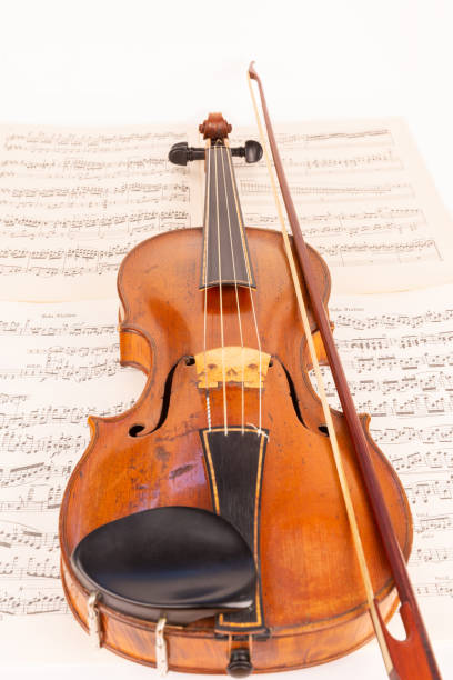 istock Baroque Violin and baroque bow with music sheets in the background 1414010390