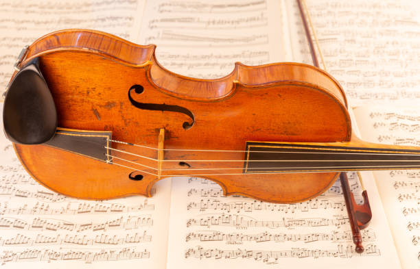 istock Baroque Violin and baroque bow with music sheets in the background 1414010406