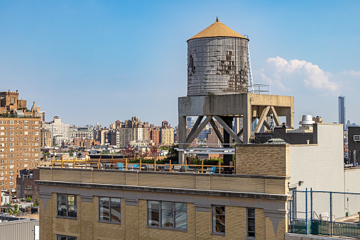 High Line Park, Manhattan, New York, NY, USA - July 1, 2022: Classic wooden water tank on a roof against a blue sky
