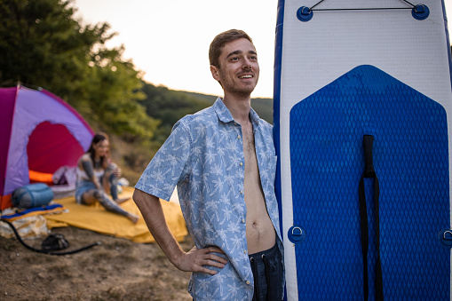 Portrait of young Caucasian man carrying paddleboard