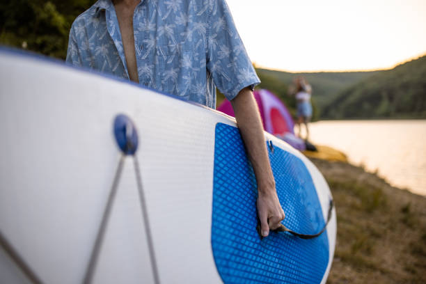 istock Unrecognizable young Caucasian man carrying paddleboard 1414011764