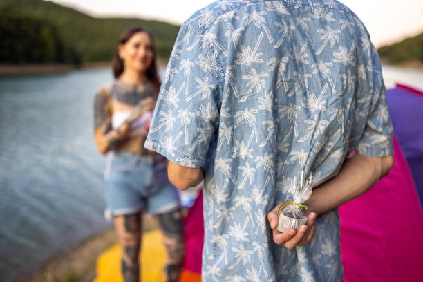 istock Young man holding a muffin behind his back, while surprising his girlfriend 1414012630
