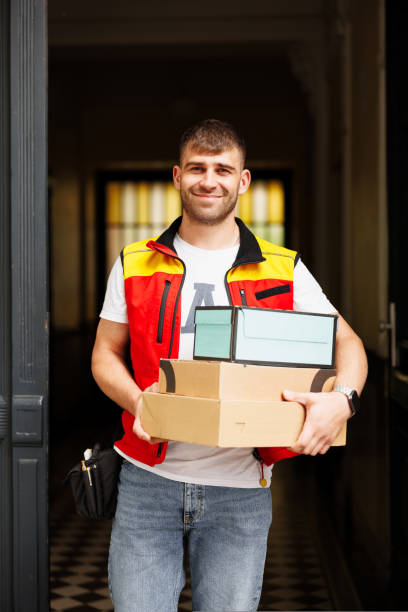 istock Image of smiling young delivery man standing with parcel box 1414015435