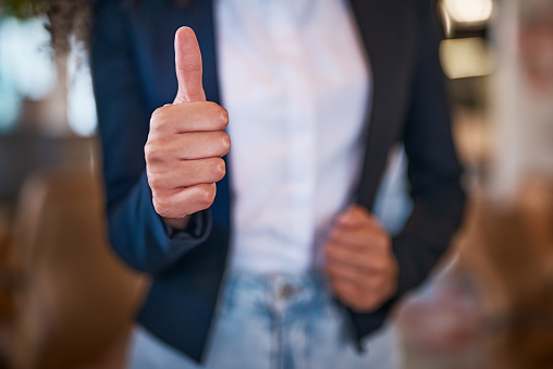 Thumbs up hand sign, symbol and gesture showing success, support and trust. Closeup finger or thumb of businesswoman endorsing idea, plan or strategy and expressing content and approval to good news