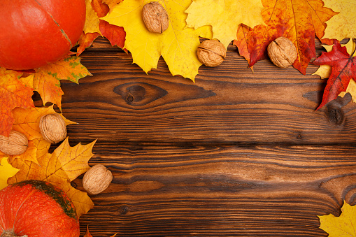 Autumn background. Yellow, orange, red fallen autumn leaves on a beautiful, brown, textured wooden background.
