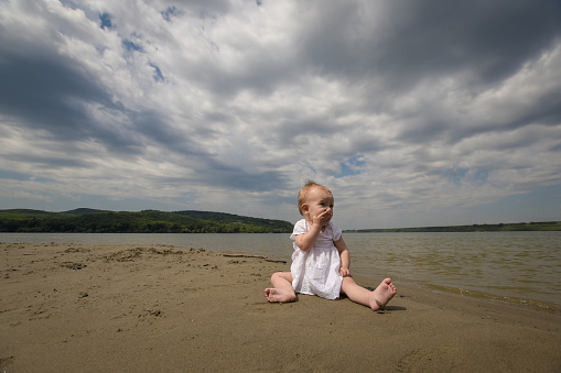 Portrait of an adorable little girl playing in the sand at the beach